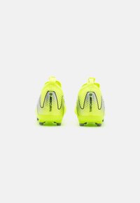 Gele voetbalschoenen met een gestructureerde bovenkant, gebogen ontwerp, opvallende branding en gevormde noppen op de zool voor grip.