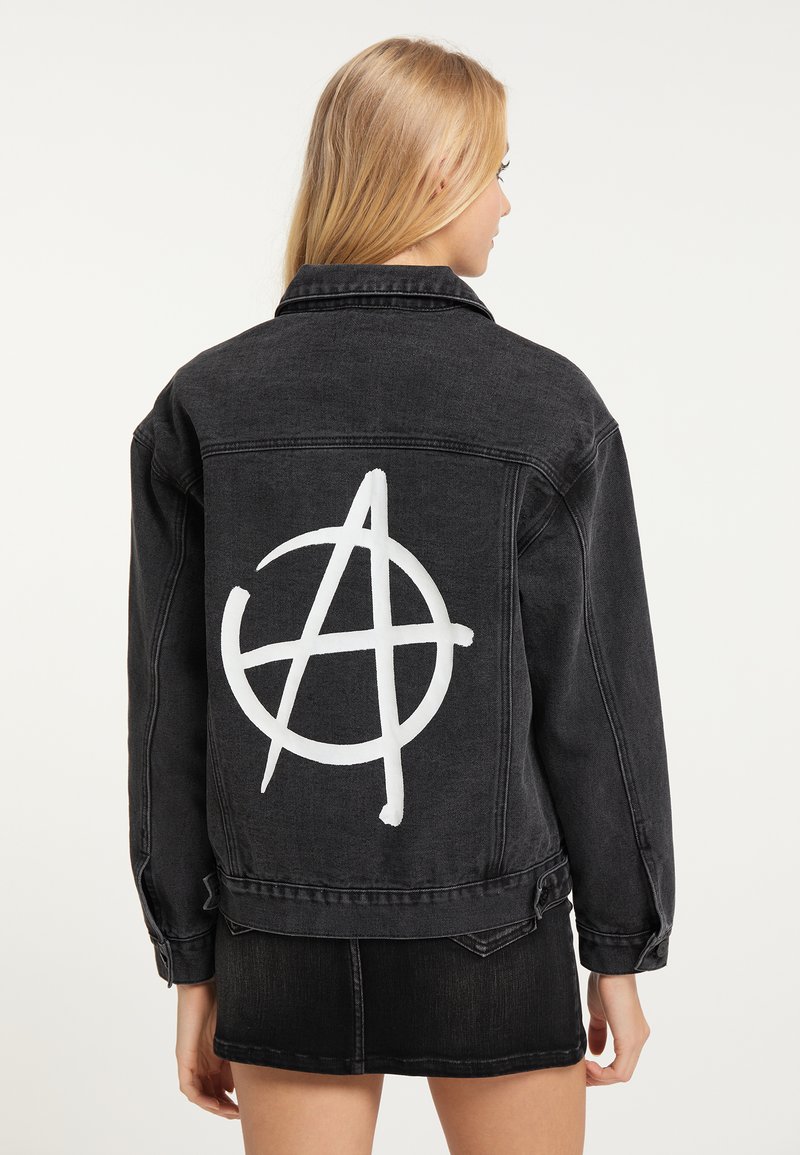 Giacca in denim nera con un simbolo di anarchia bianco stampato sulla schiena. Il design include un classico collo e dettagli con bottoni.