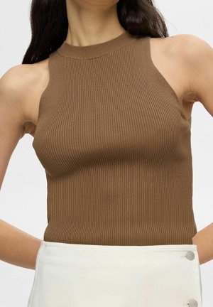 Débardeur côtelé marron avec un col montant et un design à épaule découpée, assorti à une jupe blanche avec des boutons en accent.