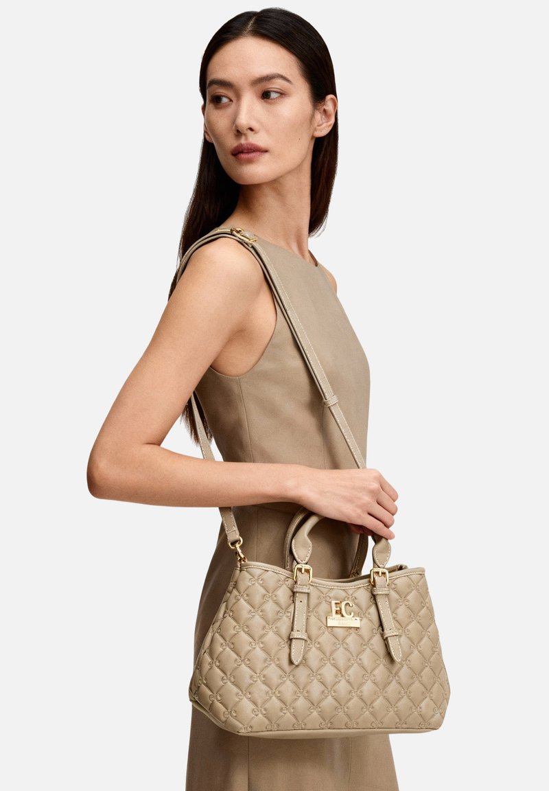 Borsa trapuntata beige in materiale sintetico con ferramenta dorata, doppio manico e tracolla regolabile. Presenta un logo impresso sul davanti.
