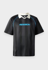 Reebok melna polo krekls ar vertikālajām svītrām, ar baltu apkakli un zilu logo uz krūtīm. Īsas piedurknes, gluda auduma tekstūra.