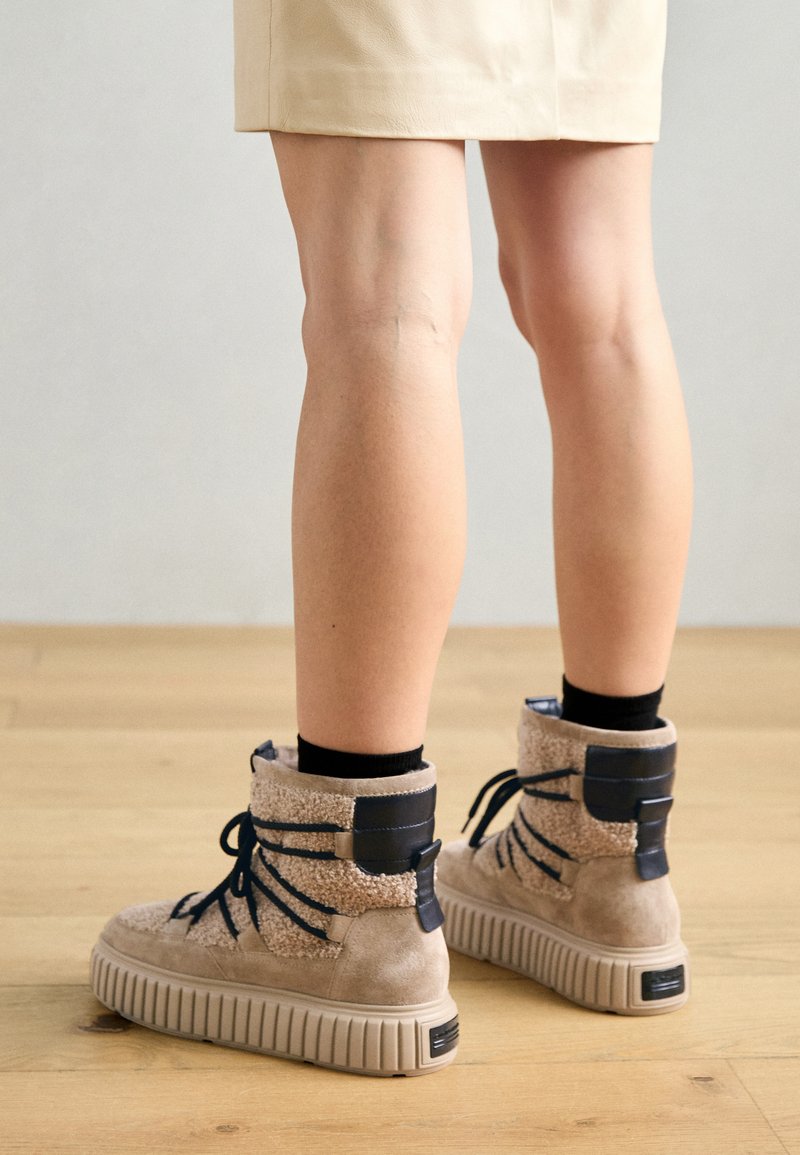 Beżowe zamszowe buty wysokie, z teksturowanymi beżowymi akcentami i niebieskimi sznurówkami, z grubą, rowkowaną podeszwą i wyściełanym kołnierzem.