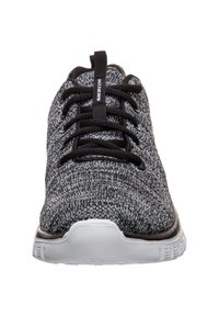 Scarpe sportive in maglia bianco e nero con punta tonda, lacci neri e suola bianca. Presentano il logo sulla linguetta e una parte superiore testurizzata.