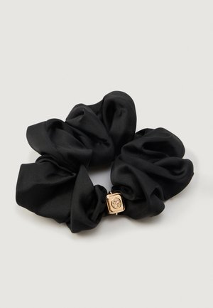 Scrunchie de cetim preto com uma textura suave, apresentando um detalhe em hardware quadrado em tom dourado com um logotipo.
