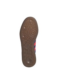 Semelle de chaussure en caoutchouc avec un motif texturé ; couleur marron avec des détails circulaires et géométriques, présentant un logo au centre.
