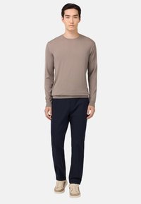 Svetlo rjava long-sleeve majica, mornarsko modri hlače in bež tenisice. Preprost dizajn s krožnim izrezom. Gladka tekstura tkanine.