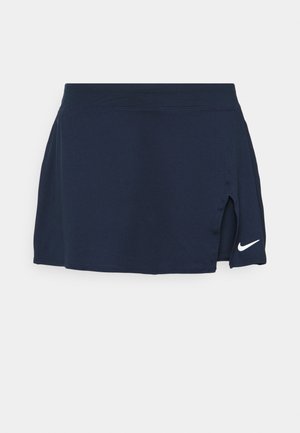 Mørkeblå sportsnederdel med sideslid og hvid Nike swoosh-logo ved højre kant mod en ensfarvet baggrund.