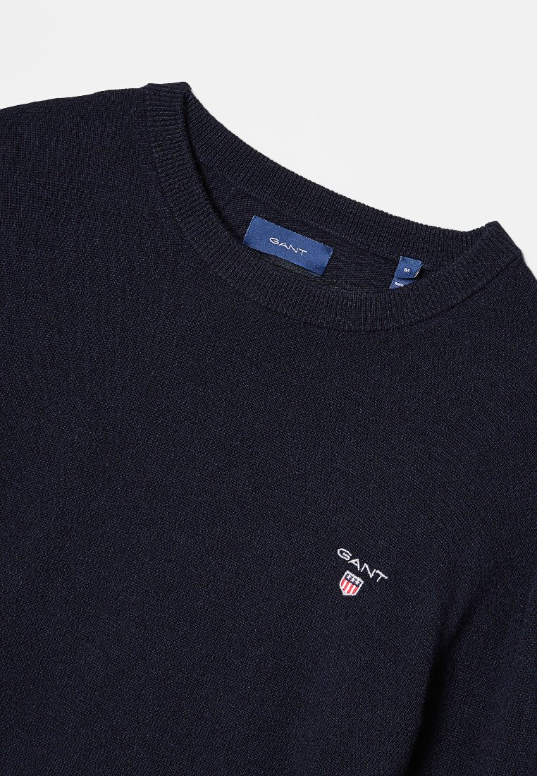 Dunkelblauer Strickpullover mit Rundhalsausschnitt, ausgestattet mit einem kleinen GANT-Logo in Weiß und Rot, aus weichem, strukturiertem Stoff gefertigt.