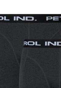 Tmavě šedé boxerky s černým elastickým pasem, na kterém je bíle napsáno "PETROL IND.". Mají hladkou texturu a přiléhavý střih.