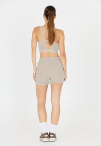 Grau Sport-BH mit einem trägerlosen Rücken Design, kombiniert mit hellgrauen Shorts. Der Stoff wirkt glatt und sportlich, ideal für das Training.