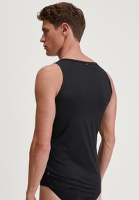 Black sleeveless tank top made of a smooth, stretchy material. Features a rounded neckline and a small branded detail at the back.