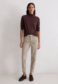 Bruine langemouwen turtleneck trui, beige slim-fit chinos en donkere instapschoenen met een getextureerde afwerking en een slim-fit ontwerp.