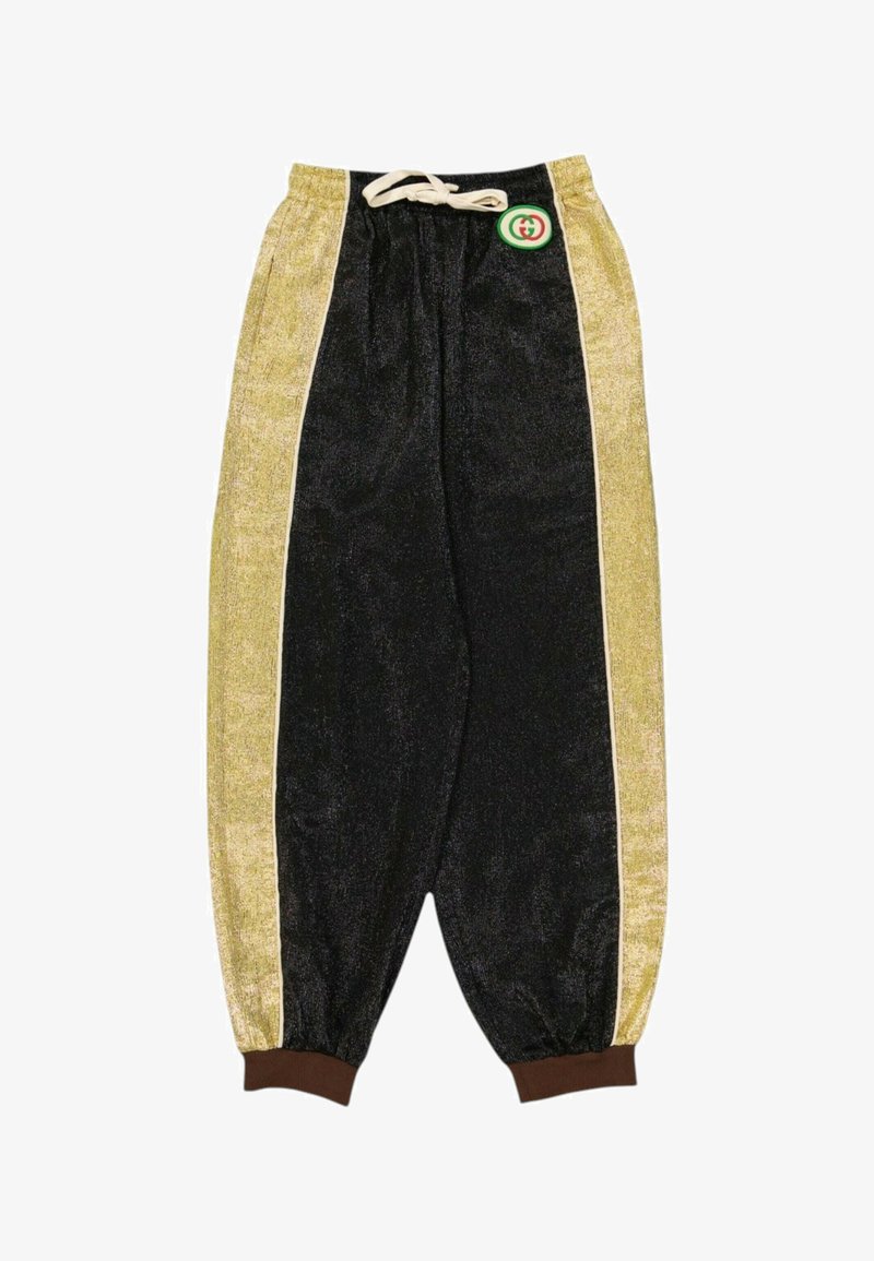 Pantalon en velours noir et or avec des poignets élastiques, une taille à cordon crème et un petit logo rond vert et rouge près de la ceinture.