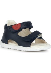 Sandalo in pelle blu con suola bianca, dotato di cinturini in Velcro, lati aperti e etichetta rossa in evidenza. Soletta perforata per ventilazione.