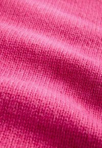 Material tricotat roz texturat, cu cusături vizibile, având fibre moi și netede și un tipar consistent pe tot parcursul.