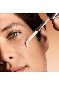 Na skórę aplikuje się przezroczysty serum za pomocą pipety. Skóra jest gładka o naturalnym odcieniu, a serum ma lekką, błyszczącą konsystencję.