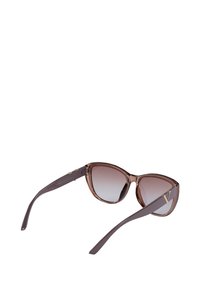 Okulary przeciwsłoneczne w kształcie kocich oczu z gradientowymi brązowymi soczewkami, przezroczystą oprawką i ciemnobrązowymi zausznikami z złotymi detalami.