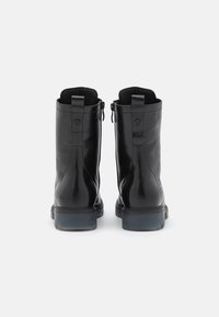 Botas de cuero negras hasta el tobillo con un acabado suave, que presentan una puntera redonda, un diseño minimalista y una suela de goma gruesa y baja.