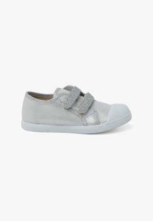 Chaussure en toile argentée avec deux bandes Velcro et un embout en caoutchouc, dotée d'une semelle blanche et de détails texturés sur le tissu.