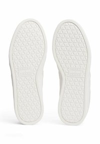 Weiße Gummisohlen von Sneakers mit einem strukturierten geometrischen Muster. Enthält geprägte Markenkennzeichnung in einem rechteckigen Feld. Abgerundete Kanten und weiße Nähte.