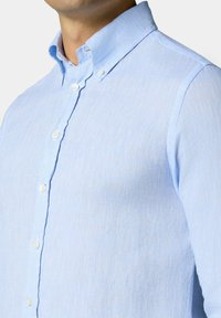 Lichtblauw linnen shirt met een button-down kraag en knopen aan de voorkant, gemaakt van een gestructureerde stof en met een getailleerde pasvorm.
