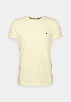 Lysegul T-shirt med korte ærmer og rund hals, med lille rød, hvid og blå logo på venstre bryst og stribet detalje på kraven.