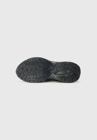 Schwarze Sportschuhsohle aus strukturiertem Gummi, mit einem Zickzackmuster, deutlichen Rillen und einem gewölbten Abschnitt für Halt und Flexibilität.