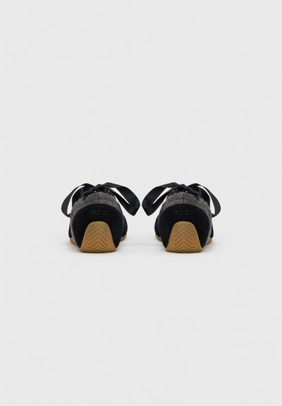 Zapatos de ante negro con un diseño texturizado, suela de goma y cordones de satén. Vista trasera que muestra una suela exterior de goma con patrón en zigzag.