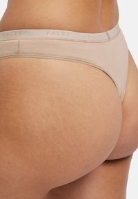 Nude-farbener Tanga aus glattem Stoff mit einem weichen elastischen Bund, der die Marke "FALKE" in einem dezenten Druck zeigt.
