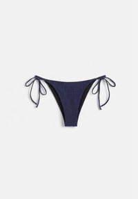 Bas de bikini à carreaux bleu marine et noir avec des liens noués sur les côtés, posé à plat sur un fond blanc.