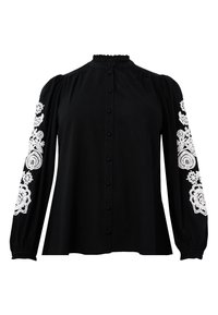 Schwarze Bluse mit langen Puffärmeln, die weiße gestickte Blumenmuster an den Ärmeln aufweist. Frontknöpfe und ein Rüschenausschnitt.