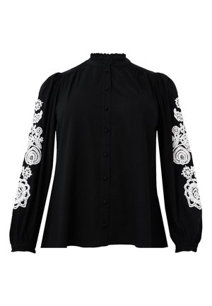 Zwarte blouse met lange pofmouwen, voorzien van witte geborduurde bloemmotieven op de mouwen. Voorzien van knopen aan de voorkant en een gerimpelde kraag.