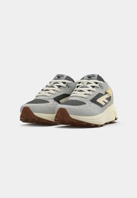 Sport shoes in light gray and dark gray, featuring synthetic and mesh materials, white laces, a textured sole, and yellow logo accent.