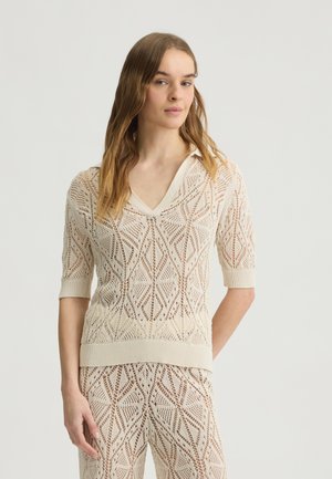 Maglione a maglia aperta a maniche corte di un beige chiaro, con scollatura a V, motivo a diamante e bordi a coste sul collo e sull'orlo.