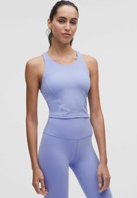 Világoslila sportos crop top, kerek nyakkivágással és versenyháttal, sima textúrával, amelyhez illeszkedő, magas derekú leggings tartozik.