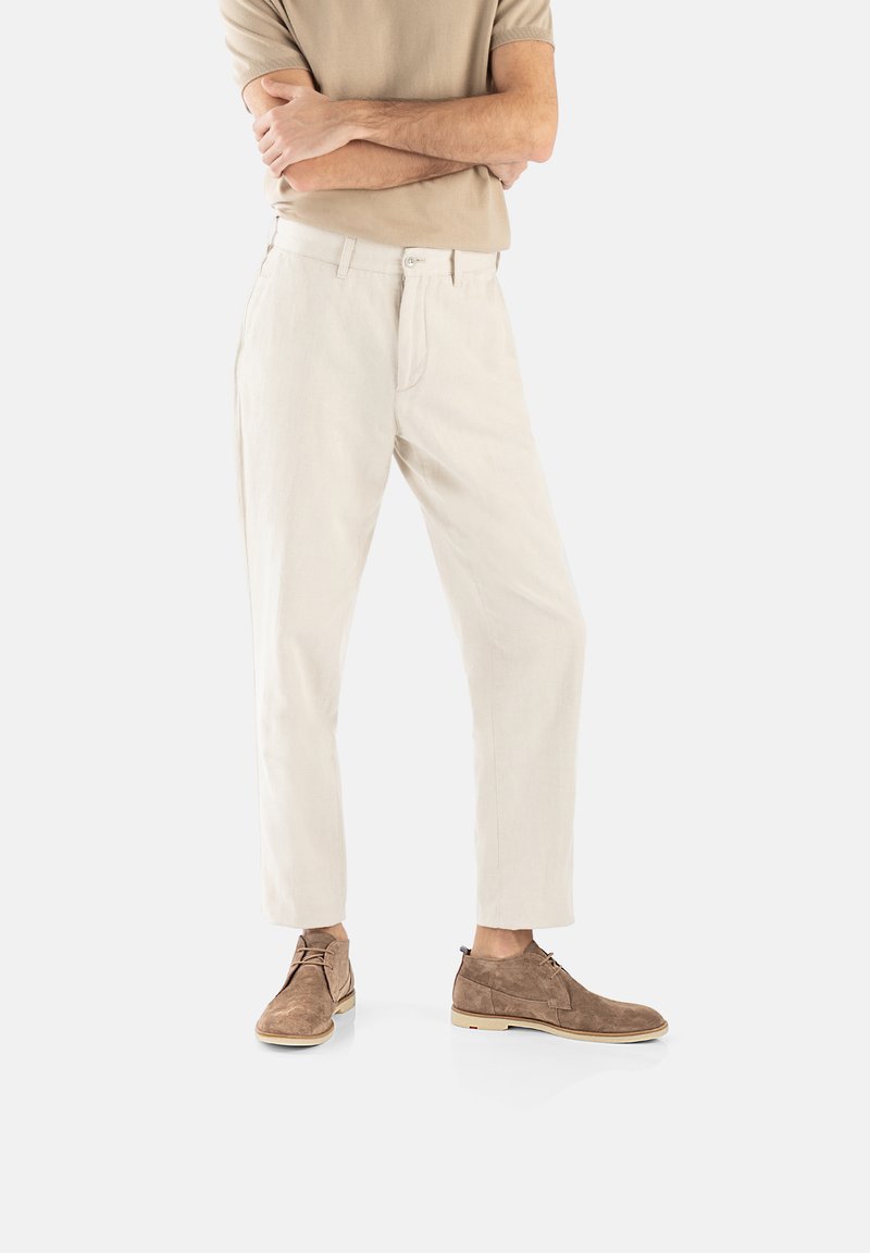 Pantaloni sartoriali color beige chiaro realizzati in lino, con fronte piatto, tasche laterali e vestibilità slim. Abbinati a scarpe in suede marroni.
