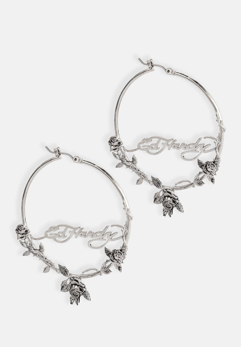 Pendientes de aro plateados con un diseño floral, que presentan rosas en relieve y el nombre "Ed Hardy" integrado en la forma. Detalles texturizados.