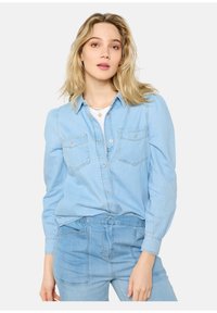 Camicia in denim blu chiaro con frontale a bottoni, due tasche sul petto e maniche lunghe. Presenta un colletto classico e dettagli di cucitura discreti.