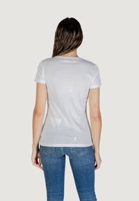 T-shirt bianco in cotone con maniche corte, scollo rotondo e una vestibilità rilassata. La vista posteriore mostra una trama liscia e una leggera lucentezza sulla pelle.