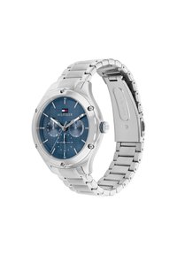 Reloj de acero inoxidable plateado con una esfera azul texturizada, marcadores de hora plateados, dos subesferas y un cierre de botón a presión. Logotipo de la marca visible.
