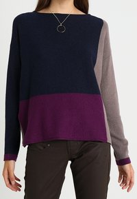 Sweter dzianinowy w kolorach granatowym, śliwkowym i taupe. Charakteryzuje się luźnym krojem, szerokim dekoltem oraz kontrastowymi blokami kolorów. Miękka tekstura i długie rękawy.
