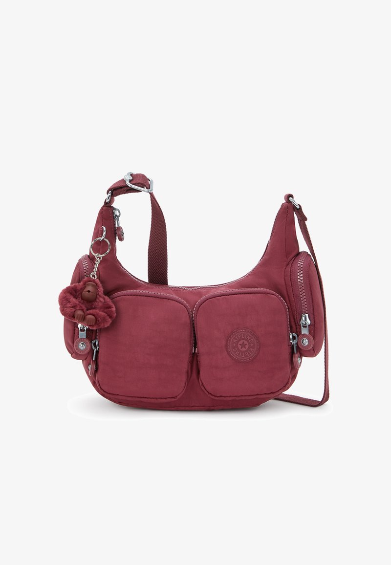 Lille maroon skuldertaske med to frontlommer, sidelommer med lynlås, justerbar rem og en blød abe-nøglering fastgjort.