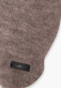 Produit en feutre gris avec une texture lisse et une forme arrondie. Comprend une étiquette en tissu noir avec le texte "PURE WIDE" attachée.