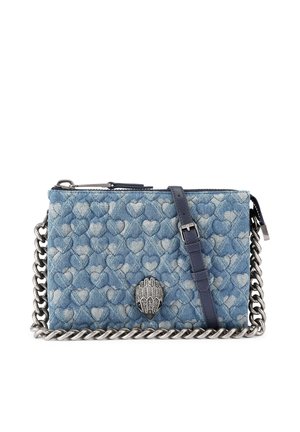 Sac bandoulière matelassé en denim bleu avec motif cœur, bandoulière en chaîne métallique argentée et fermoir décoratif en forme de main argentée.