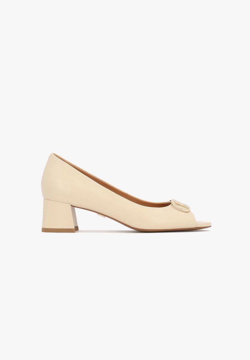 Escarpins beige en cuir avec bout ouvert, talon bloc et détail décoratif en métal sur le devant. Texture lisse et forme arrondie.