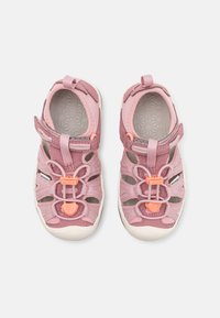 Pink outdoor sandals with a mesh upper, adjustable strap, and elastic laces. Features a white rubber sole with a textured pattern.