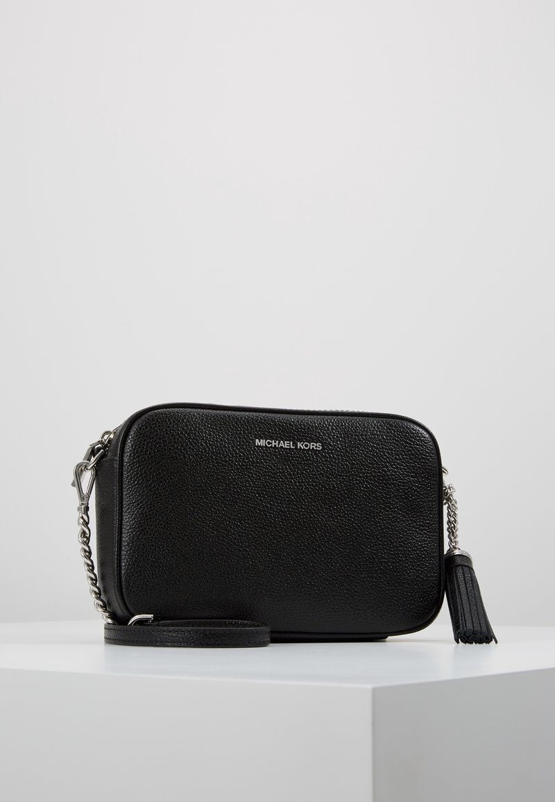 Schwarze Leder-Crossbody-Tasche mit strukturierten Oberflächen, silberner Hardware, abnehmbarem Trageriemen und einem Quastenakzent. Markenlogo auf der Vorderseite.