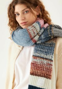 Mehrfarbiger gestrickter Schal mit blauen, rosa und rostfarbenen Streifen sowie einem strukturierten Muster. Mit einem leichten Stoffetikett an einem Ende versehen.