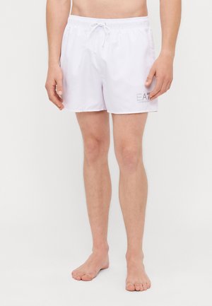 Shorts de baie albe cu talie elastică și șnur. Au logo-ul "EA7" în gri pe marginea inferioară. Textură de material neted.