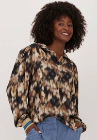 Langsleeve, overhemd met knopen in een bruin en zwart abstract patroon, met een kraag en contrasterende manchetten met blauwe strepen.